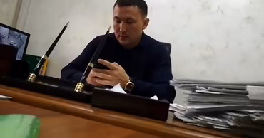 A man sitting at an office desk with documents, identified as the former bailiff.