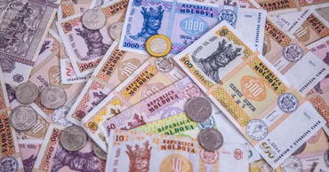 A collection of various Moldovan Leu banknotes and coins scattered on a surface.