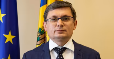 Portrait of Igor Grosu, Speaker of the Parliament of Moldova, with flags in the background.