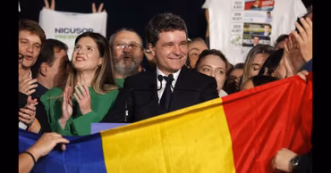Nicușor Dan smiling at a public event with supporters and a Romanian flag.
