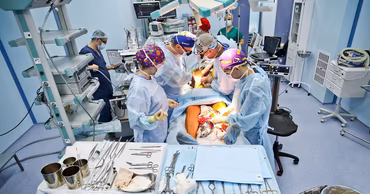 A team of surgeons performing a complex operation in a modern hospital operating room.