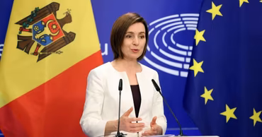 Maia Sandu speaking at a podium with Moldovan and European Union flags in the background.