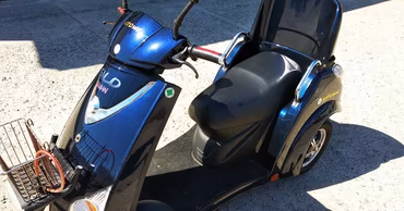 A blue electric moped parked on a concrete surface.