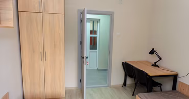 A modern, renovated dormitory room with wooden furniture and a desk at the Technical University of Moldova.