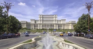 The Palace of the Parliament in Bucharest, Romania, seen from the street with a fountain.