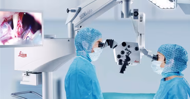 Surgeons using a Leica surgical microscope in an operating room.