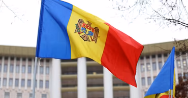 The flag of Moldova waving in front of a government building.
