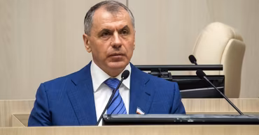 Dmitri Constantinov sitting at a desk in a formal setting.