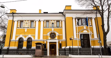 A yellow historic building with white columns, representing an embassy office.