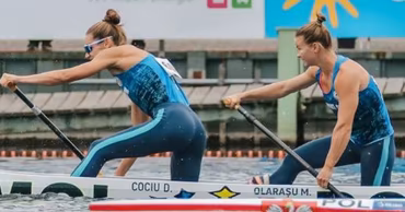 Daniela Cociu and Maria Olarașu paddling in a canoe during a competition.