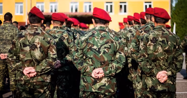 A group of Moldovan soldiers in camouflage uniforms and red berets standing in formation.