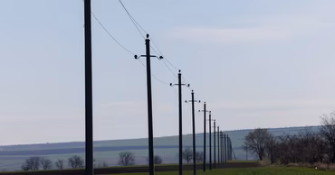 A row of high-voltage power line poles stretching across a rural landscape.