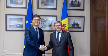 Igor Grosu shaking hands with a foreign official in front of Moldovan and EU flags.
