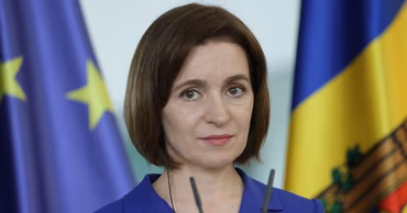 Maia Sandu, President of Moldova, speaking at a press conference with EU and Moldovan flags in the background.