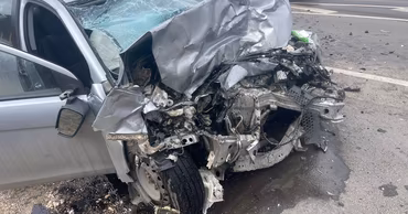 A silver car with severe front-end damage after a traffic accident.