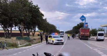 A motorcycle lying on a road at an accident scene with police cars present.