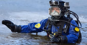 A rescue diver in full gear working in cold water.