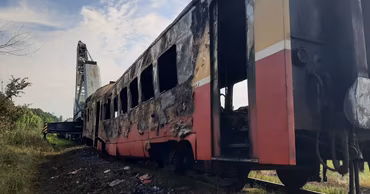A burnt and dilapidated train carriage in a field, representing poor living conditions.