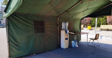 A green GIGS tent set up as a heat relief point with a water cooler.