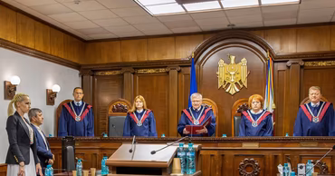 Judges in robes sitting in a Moldovan courtroom during a legal proceeding.