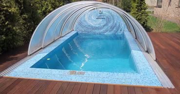 A private outdoor swimming pool with a retractable cover in a residential backyard.