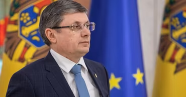 Igor Grosu, President of the Moldovan Parliament, standing in front of Moldovan and EU flags.