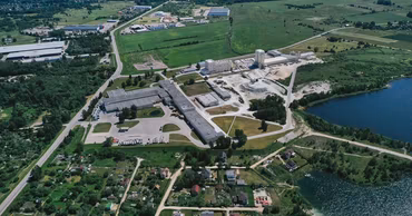 Aerial view of an industrial complex with buildings, roads, and surrounding green fields.