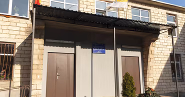 The entrance of a school building in Moldova with a sign reading Scoala Auxiliara.