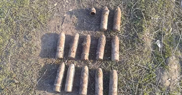 Several rusty unexploded artillery shells lying on the ground.
