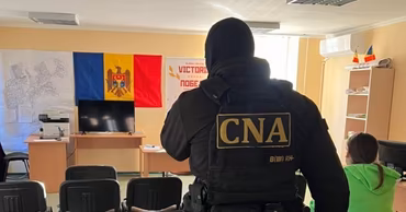 A CNA officer in tactical gear standing in an office during a search operation.