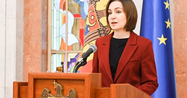 Moldovan President Maia Sandu speaking at a podium with national and EU flags.
