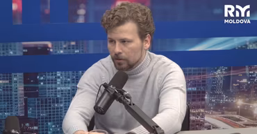 Dan Perciun sitting at a desk with a microphone during an interview.