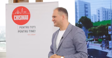 Ion Ceban standing in front of a banner with the Chisinau logo.
