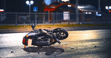 A crashed motorcycle lying on a wet asphalt road at night.
