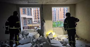 Ukrainian emergency responders inspecting a damaged apartment building after a missile strike.