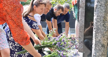 People laying flowers at a memorial monument in Moldova to commemorate victims of political repression.