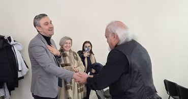 Cristian Jardan shaking hands with Alexandru Munteanu in an indoor setting.