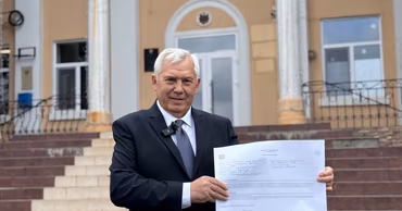 Valentin Gaidarji standing in front of a building holding a document.