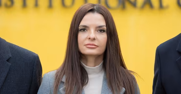 Evghenia Gutul standing in front of a yellow background.