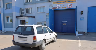 A white car parked in front of a vehicle diagnostic and inspection station.