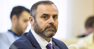 A portrait of Emil Ceban, a man with a beard wearing a suit and tie.