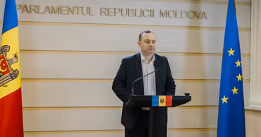 Vlad Batrincea speaking at a podium in the Parliament of Moldova.