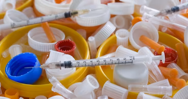 A close-up of various medical waste items including syringes and plastic caps.