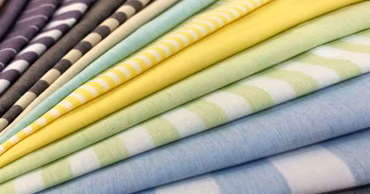 A stack of various colorful striped and solid fabric samples.