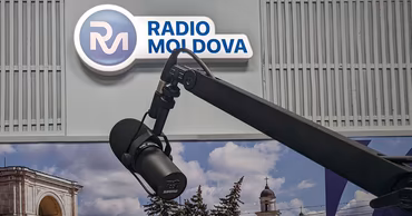A professional microphone in the Radio Moldova studio with the station logo in the background.