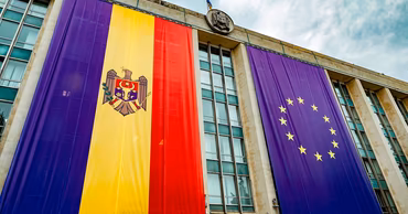Moldovan government building facade decorated with large Moldovan and European Union flags.