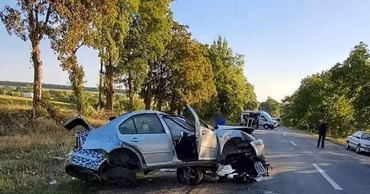 A heavily damaged silver car off the road after a traffic accident.