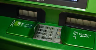 Close-up of a green ATM keypad and cash slots.