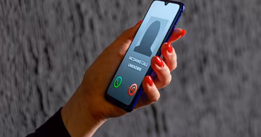 A person holding a smartphone showing an incoming call from an unknown number.