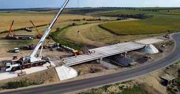 Aerial view of a bridge construction site with a crane and workers.